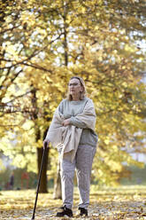 Senior woman walking with stick at public park - ABIF01665