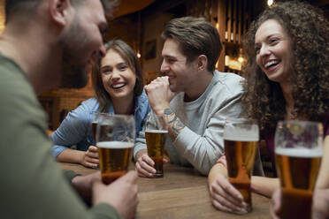Eine Gruppe glücklicher Freunde trinkt Bier und unterhält sich in einer Kneipe - ABIF01677