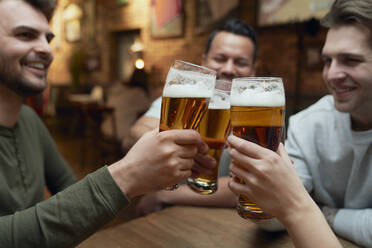 Friends meeting in a pub and clinking beer glasses - ABIF01688