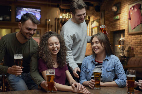 Lächelnde Freunde beim Bier in einer Kneipe - ABIF01691
