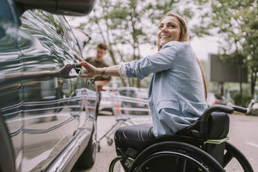 Happy disabled woman opening car door - MFF08997