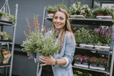Glückliche junge Frau kauft Pflanzen im Gartencenter - MFF09000