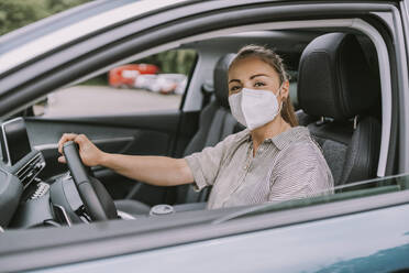 Young woman with protective face mask driving car - MFF09006