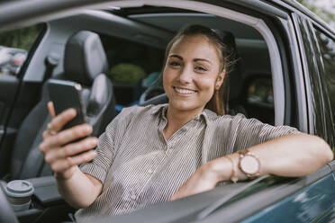 Glückliche Frau mit Smartphone auf dem Fahrersitz im Auto sitzend - MFF09016