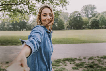 Lächelnde junge Frau, die im Park an der Hand ihrer Freundin zieht - MFF09052