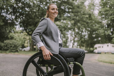 Happy young businesswoman sitting in wheelchair - MFF09064