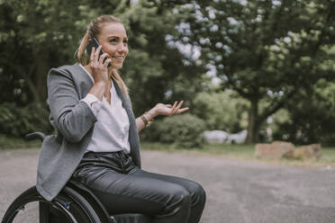 Behinderte Geschäftsfrau telefoniert mit Handy im Park - MFF09065