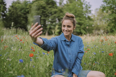 Lächelnde Frau nimmt Selfie durch Smartphone in Wiese - MFF09073