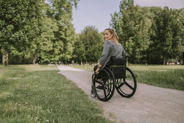 Junge Frau sitzt im Rollstuhl im Park - MFF09079