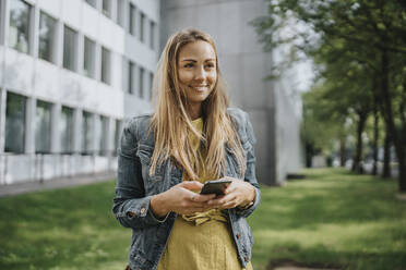 Junge Frau mit Smartphone im Park - MFF09083