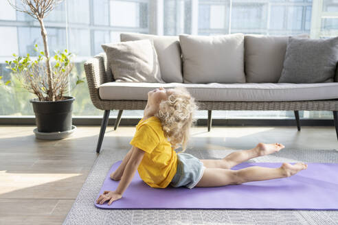 Mädchen übt Cobra Pose Yoga vor dem Sofa zu Hause - SVKF00104