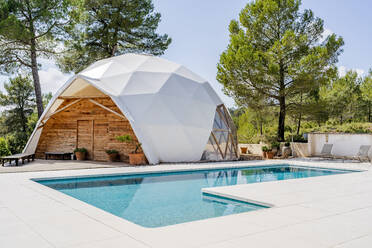 Außenansicht eines kuppelförmigen Zimmers am Swimmingpool eines Hotels an einem sonnigen Tag - DLTSF02893