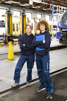 Lächelnder Ingenieur mit Aktenordner neben einem Kollegen in der Fertigungsindustrie - FKF04780