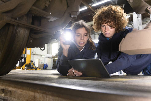 Ingenieur mit Auszubildendem bei der Analyse von Einschienenbahnrädern mittels Tablet-PC in der Fabrik - FKF04816