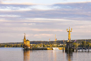Deutschland, Baden-Württemberg, Konstanz, Hafen am Bodenseeufer in der Abenddämmerung mit Leuchtturm und Statue von Imperia im Hintergrund - WDF06882