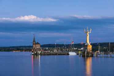 Deutschland, Baden-Württemberg, Konstanz, Hafen am Bodenseeufer in der Abenddämmerung mit Leuchtturm und Statue von Imperia im Hintergrund - WDF06884