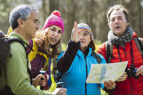 Frau mit Karte führt Freunde im Wald - JCCMF06069