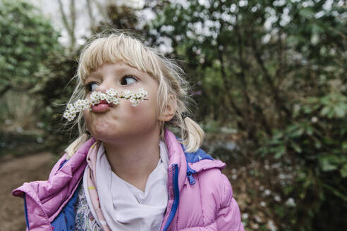 Cute girl making mustache with white flowers - TYF00117