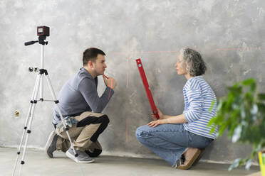 Man and woman discussing by gray wall at new home - SEAF00814