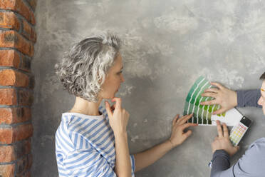 Frau mit Freund wählt Farbe aus Farbpalette auf grauer Wand - SEAF00826