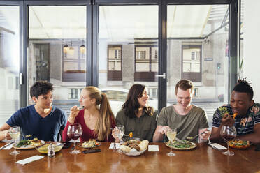 Smiling friends enjoying meal in restaurant - ISF25617