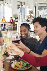 Lächelnde Freunde stoßen mit Wein im Restaurant an - ISF25625