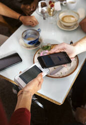 Close-up of man paying with smart phone in restaurant - ISF25627