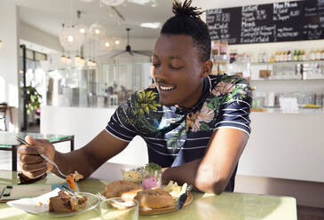 Lächelnder Mann genießt das Frühstück im Café - ISF25632