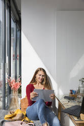 Smiling woman with laptop in restaurant - ISF25642