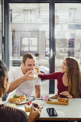 Smiling couple enjoying breakfast in restaurant - ISF25643