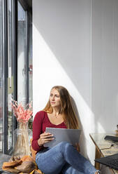 Nachdenkliche Frau schaut durch ein Fenster in einem Restaurant - ISF25644