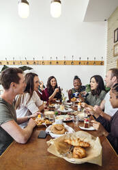 Group of smiling friends enjoying breakfast in restaurant - ISF25646