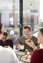 Smiling friends enjoying breakfast in restaurant - ISF25651