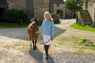 Lächelnde Frau mit Pony auf dem Bauernhof - ISF25662