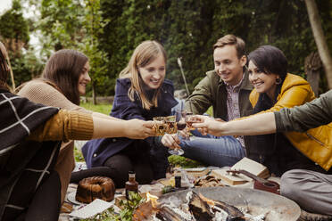 Group of friends toasting around fire pit in garden - ISF25678