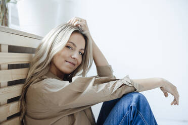 Smiling woman with blond hair sitting at home - JOSEF08523