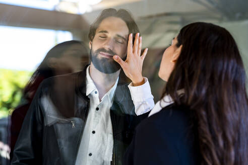 Woman touching man separated through glass pane - DLTSF02897