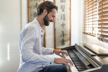 Man playing piano at home - DLTSF02907