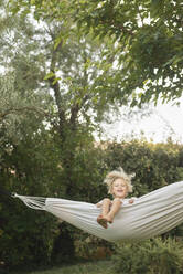 Girl swinging in hammock at garden - SVKF00115