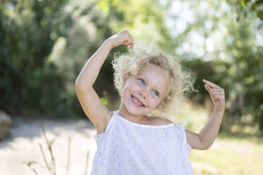 Playful girl with hands raised pointing at herself in garden - SVKF00124