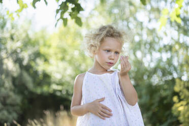 Curious girl looking at berry in garden - SVKF00126