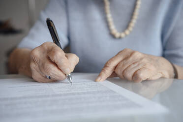Hände einer älteren Frau, die mit einem Stift auf Papier schreibt - JOSEF08568