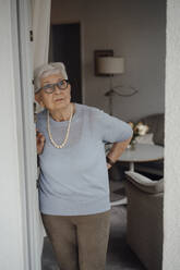 Ältere Frau mit weißem Haar steht vor der Wohnungstür - JOSEF08571