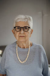 Smiling senior woman with white hair standing at home - JOSEF08572