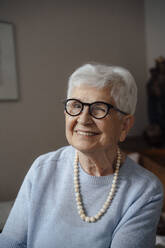 Happy senior woman wearing eyeglasses winking at home - JOSEF08588