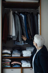 Ältere Frau bei der Auswahl der Kleidung im Kleiderschrank zu Hause - JOSEF08601