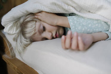 Girl sleeping under blanket on bed at home - TYF00124