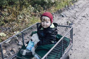 Junge mit Spielzeug im Gartenwagen sitzend - ACTF00221