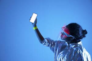 Woman wearing smart glasses holding smart phone against blue background - VPIF05811