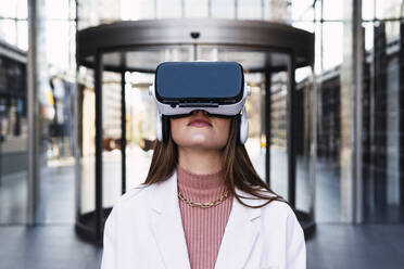 Geschäftsfrau mit Virtual-Reality-Simulator vor einem Bürogebäude - PNAF03713
